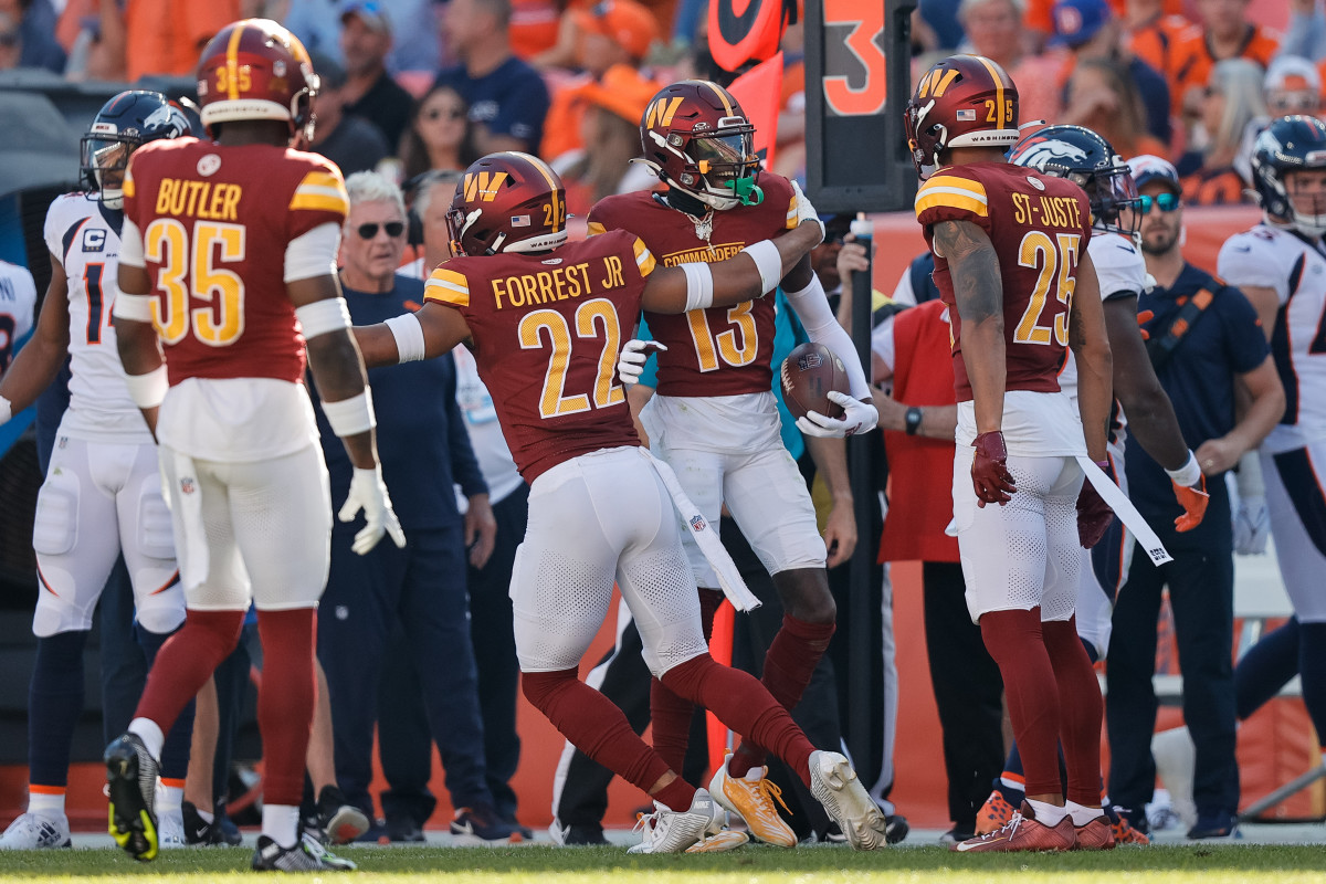 Washington Commanders cornerback Emmanuel Forbes Jr. (13) celebrates his interception with safety Darrick Forrest (22) and cornerback Benjamin St-Juste (25) and safety Percy Butler (35) in the third quarter against the Denver Broncos at Empower Field at Mile High.